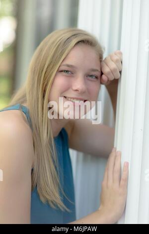 Teenage girl leaning a white building pillar