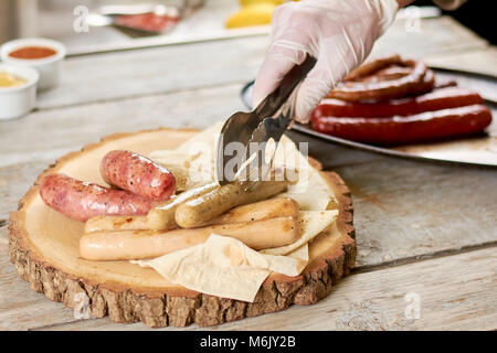 Chef putting grilled sausages on platter. Stock Photo