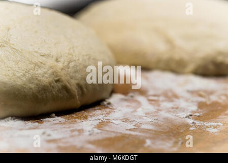 horizontal image of two rounds of rustic, crusty hearty bread rising on flour covered wooden board. selective focus Stock Photo