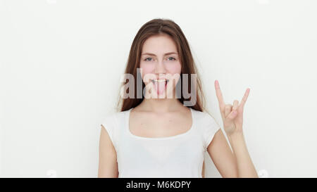 Pretty funny young girl showing tongue and rock gesture Stock Photo