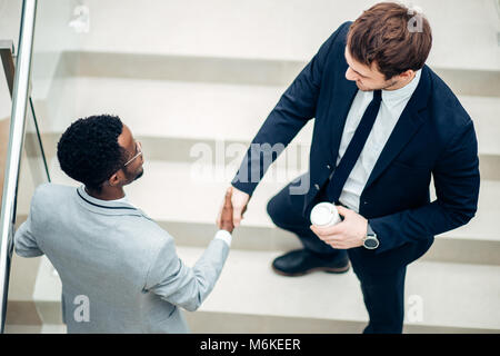two multiracial businessmen handshaking in modern office for end of great deal Stock Photo
