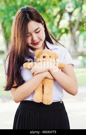teen girl playing with bear toy with nature background. Stock Photo