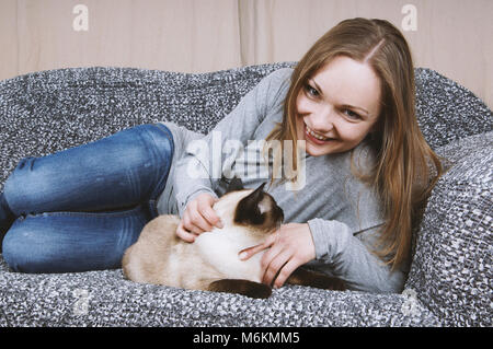 happy young woman relaxing on couch with cat Stock Photo