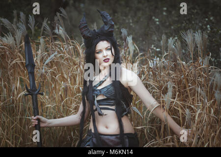 Beautiful wild girl with horns stands in the thickets Stock Photo