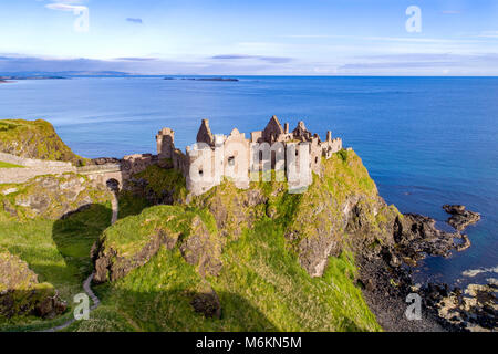Ruins of medieval Dunluce Castle on a steep cliff. Northern coast of County Antrim, Northern Ireland, UK. Aerial view.
