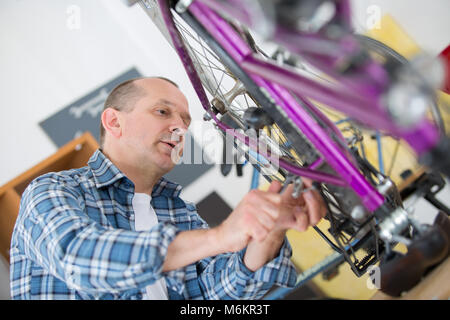 handyman fixing bike wheel in his garage Stock Photo