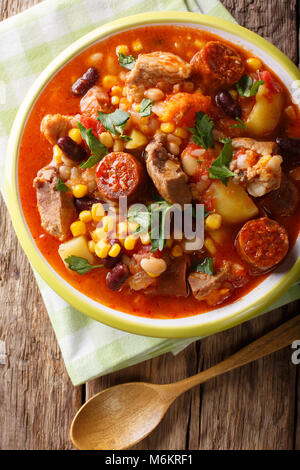 National cuisine of Cape Verde: Cachupa with meat, chorizo and vegetables close-up on a plate on a table. Vertical top view from above Stock Photo