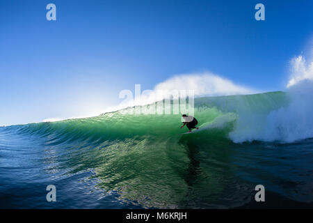 Surfing surfer tube rides ocean wave morning silhouetted water action photo unidentified Stock Photo