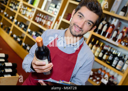 smiling man seller having bottle of wine in shop Stock Photo