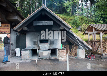 German old men use firewood stove old style cooking bread at restaurant near Mummelsee lake in Black Forest or Schwarzwald on September 9, 2017 in Stu Stock Photo