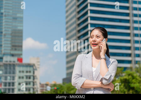 successful beautiful business woman talking on the phone call on the street outside of the office with blue sky sunny day. Stock Photo