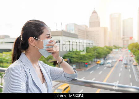 beautiful businesswoman feels allergy from bad air quality pollution and wear a mask standing outside. Stock Photo