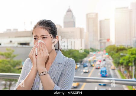 charming office lady got allergy and runny nose from air pollution and using paper tissue on peak time traffic travel. Stock Photo