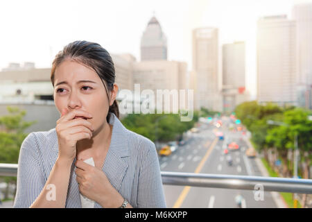 beautiful Asian young woman got a cough and ill from air pollution and using paper tissue on peak time traffic travel. Stock Photo