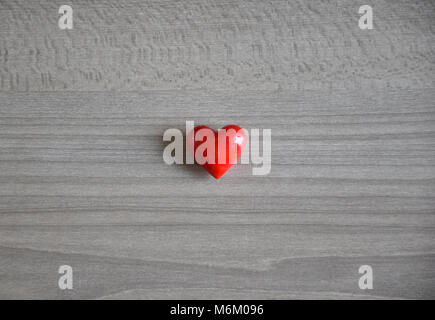 Small red love heart pebble stone against a simple background Stock Photo