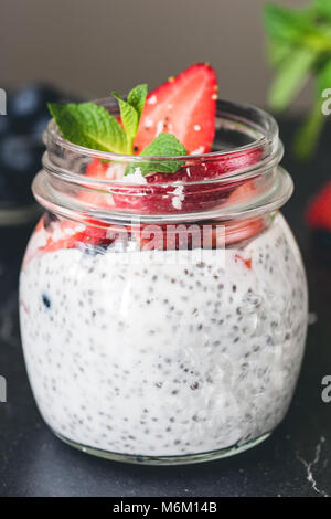 Chia pudding with fresh strawberries and blueberries in jar. Closeup view Stock Photo