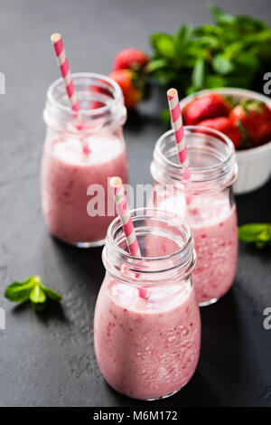 Strawberry smoothie in bottles with drinking straw. Selective focus. Healthy lifestyle, fitness, detox, dieting, clean eating, vegan, vegetarian conce