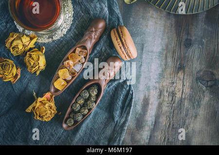 A Cup of brewed black tea. Two ceramic spatulas with caramel sugar and Rolled leaves in a large pearl. Chinese tea from Yunnan. Bi Lo Chun. Stock Photo