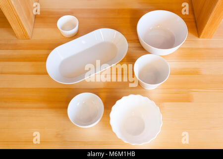 Beautiful new white ceramic plates of different sizes on a wooden table Stock Photo