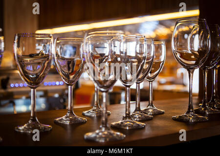 Beautiful new glasses for wine from glass stand in even rows on a wooden table in a restaurant Stock Photo