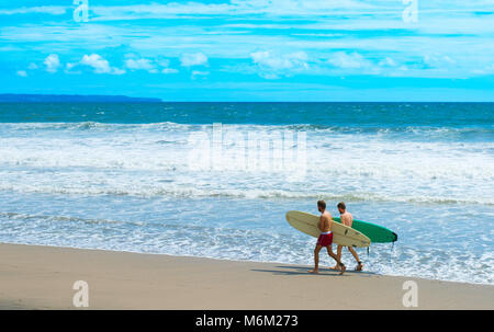 CANGGU, BALI ISLAND, INDONESIA - JAN 19, 2017: Surfers walking with surfboard on the beach. Bali island is one of the worlds best surfing destinations Stock Photo