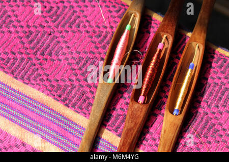 colorful thread in wooden bobbin on silk fabric, traditional weaving of Thai silk Stock Photo