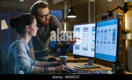 Female UX Architect Has Discussion with Male Design Engineer, They Work on Mobile Application Late at Night, She Drinks Coffee. Loft, modern office. Stock Photo