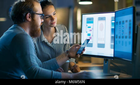 Handsome Male and Beautiful Female Mobile Application Designers Test and Discuss New App Features. They Work on a Personal Computer with Two Displays Stock Photo
