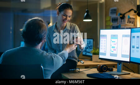 Beautiful Female and Handsome Male Video Editors Discuss Footage They're Working On. They Enjoy Working Together in a Creative Studio. Stock Photo