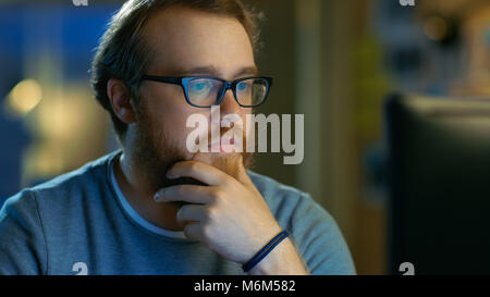 Young Bearded Creative Man Thinks on a Problem While Working on His Personal Computer. Stock Photo
