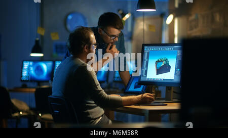 Two Male Game Developers Discuss Game Level Drawing, One Uses Graphic Tablet. They Work Late at Night in a Loft Office. Stock Photo