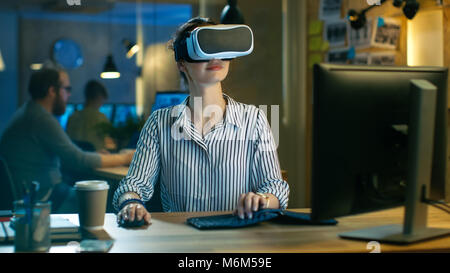 Beautiful Female Virtual Reality Engineer/ Developer Wearing VR Headset Creates Content. She Works in a Creative Designers Studio. Stock Photo
