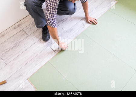 carpenter worker installing laminate flooring in the room Stock Photo