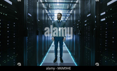 Curios IT Engineer Standing in the Middle of a Working Data Center Server Room. Stock Photo