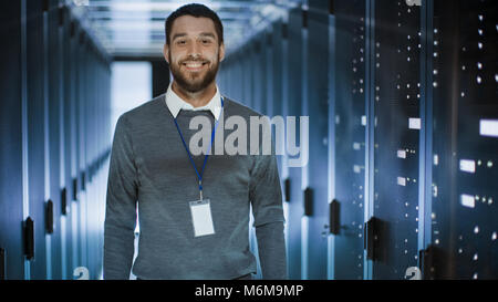 Portrait of an IT Engineer, he Smiles and Folds His Arms on a Chest. He's Working in Data Center Full of Rack Servers. Stock Photo