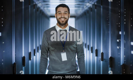 Portrait of an IT Engineer, he Smiles and Folds His Arms on a Chest. He's Working in Data Center Full of Rack Servers. Stock Photo
