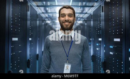 Portrait of a Curios, Positive and Smiling IT Engineer Standing in the Middle of a Large Data Center Server Room. Stock Photo