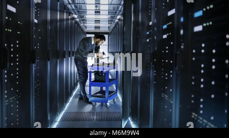 IT Engineer Works on a Laptop and Scans Hard Drives That are Lying on a Crash Cart. He Works in Data Center. Stock Photo