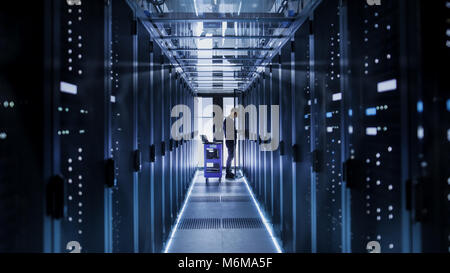 IT Engineer With Crash Cart Puts Hard Drives into Open Rack Server Cabinet. He's Working in Big Data Center. Stock Photo