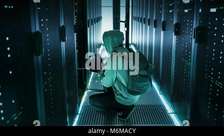 Hacker With Laptop Connects to Rack Server and  Steals Information from Corporate Data Center. Stock Photo
