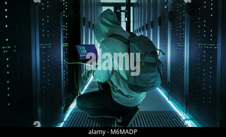 Hacker With Laptop Connects to Rack Server and  Steals Information from Corporate Data Center. Stock Photo