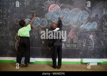 Two school kids drawing on the blackboard in classroom Stock Photo