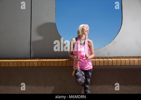 Caucasian woman posing with jump rope draped around neck Stock Photo