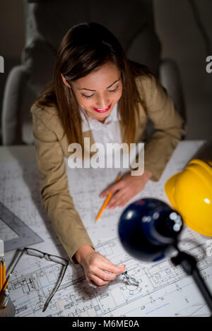 Young woman architect constructor analyzing blueprint at desk in office. Top view. Stock Photo