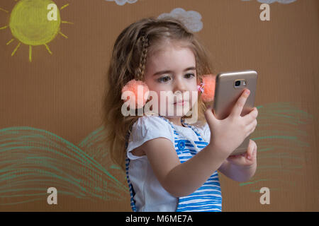 Adorable modern little kid, blonde toddler girl playing with mobile phone. new digital technologies in the hands of a child Stock Photo