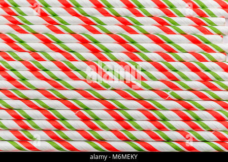 Red, green and white plastic striped straws on a white background, close up. Stock Photo