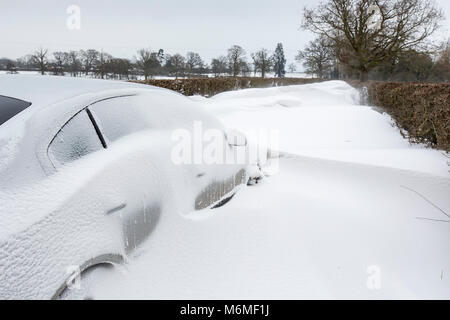 A car stuck in a snow drift in a country lane in Redditch, UK Stock Photo