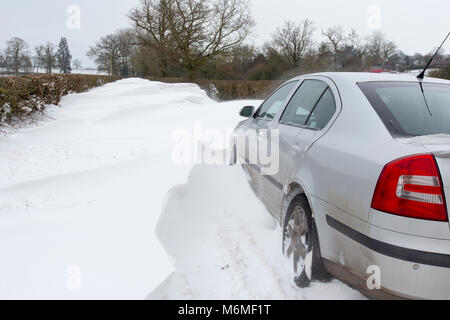 A car stuck in a snow drift in a country lane in Redditch, UK Stock Photo