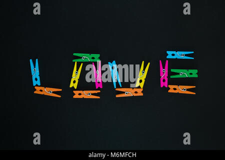 Love text made of colorful wooden clothes pegs on black background Stock Photo