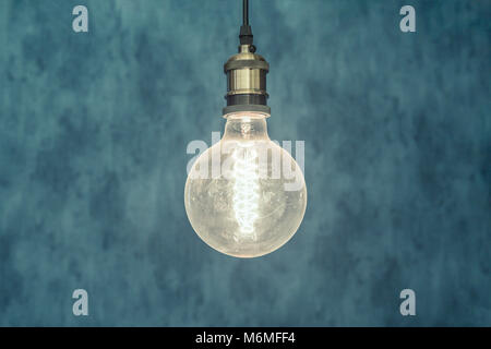 Decorative antique edison style light bulb against blue background. Stock Photo